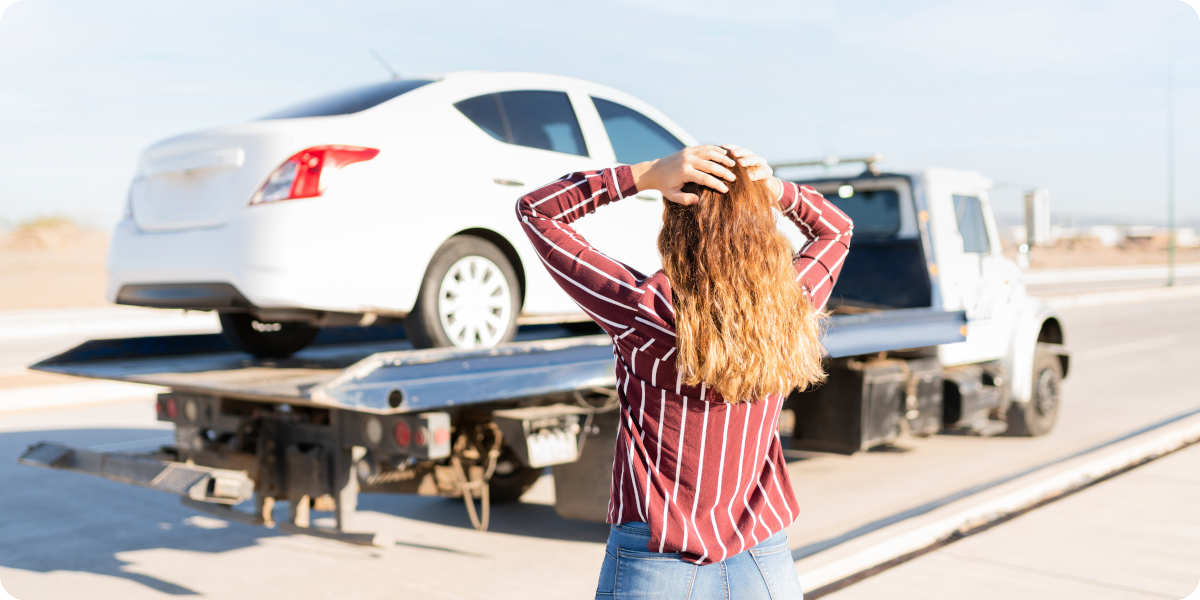 Frau sieht zu wie Ihr Auto abgeschleppt wird.