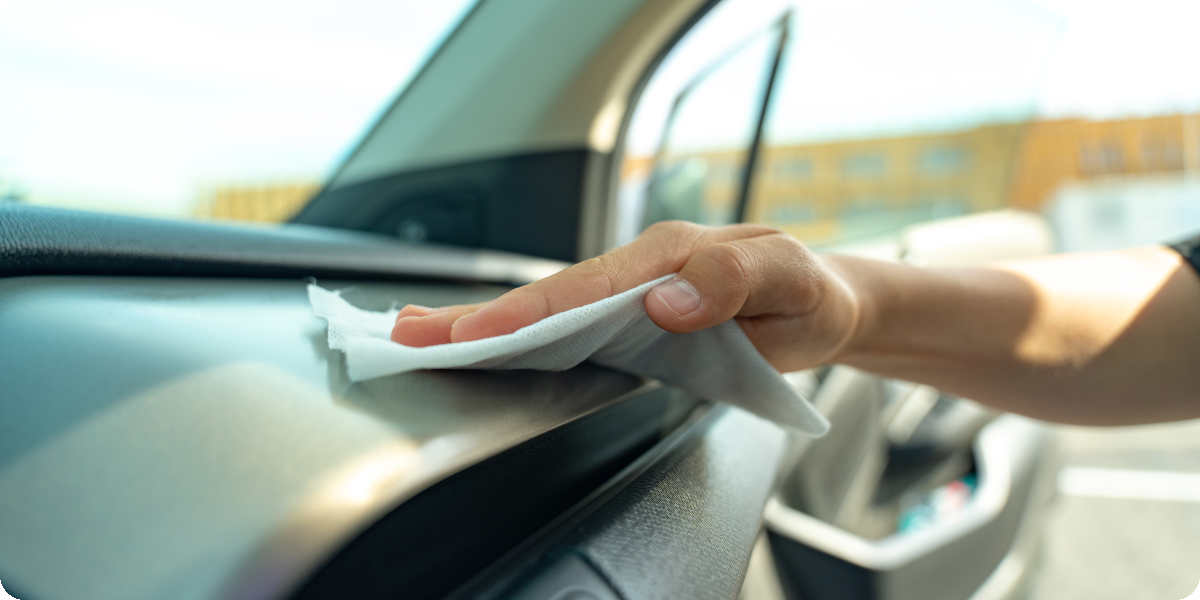 Ein Armaturenbrett wird im Auto mit einem Mikrofasertuch abgewischt.