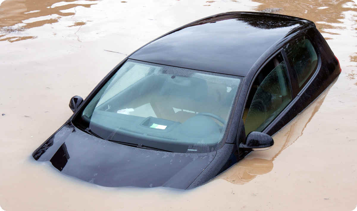 Ein schwarzer PKW steht auf der Straße unter Wasser.