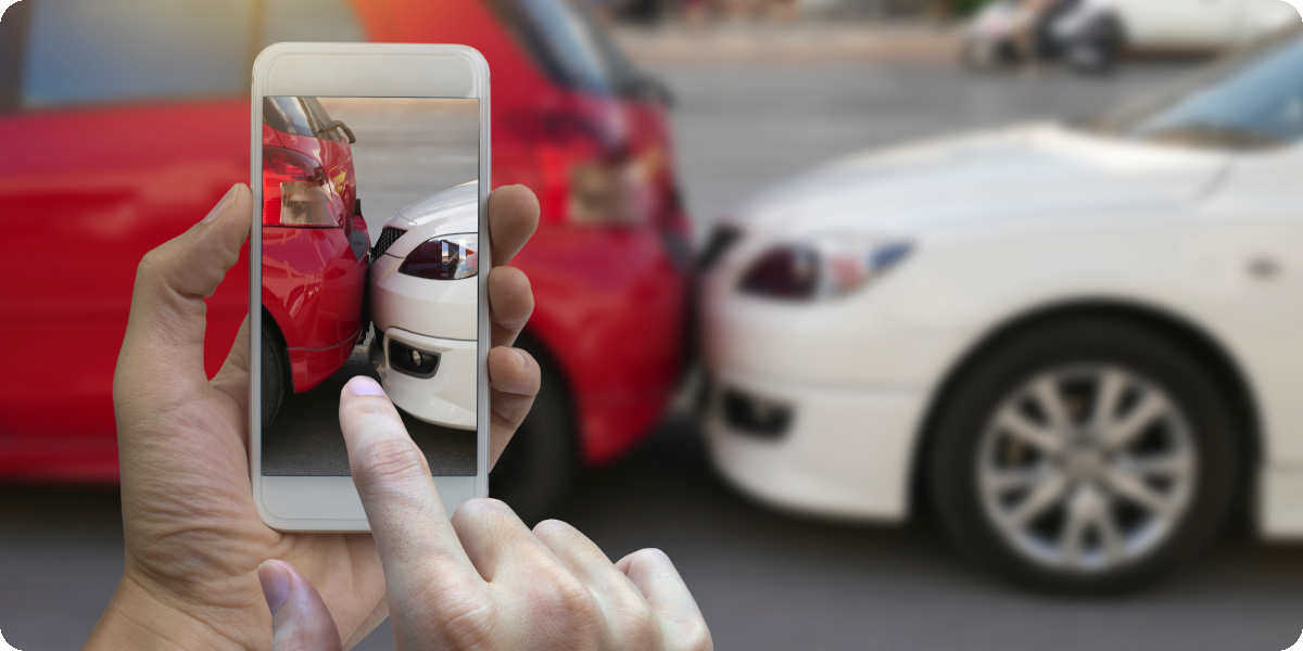 Ein Auto ist auf ein anderes aufgefahren und eine Person fotografiert den Schaden.