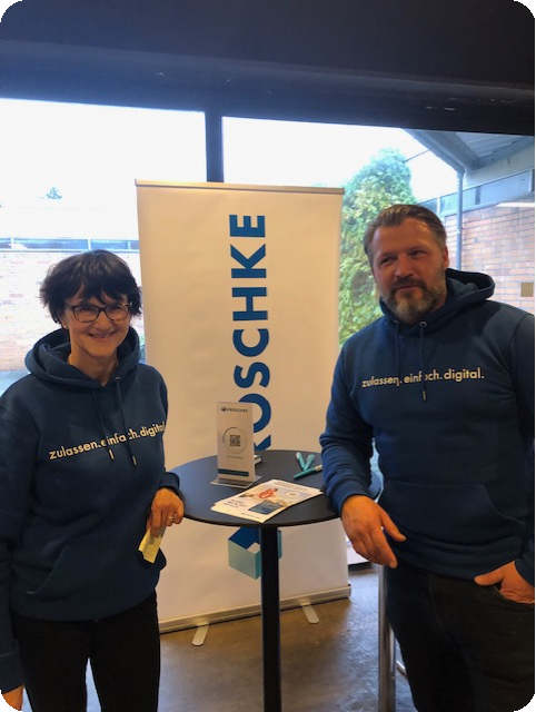 Mitarbeiter von Kroschke stehen am Messestand in Prinovis.