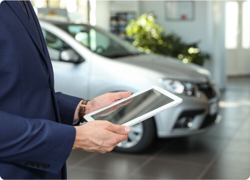 Ein Automobilverkäufer hält im Autohaus ein Tablet in der Hand.